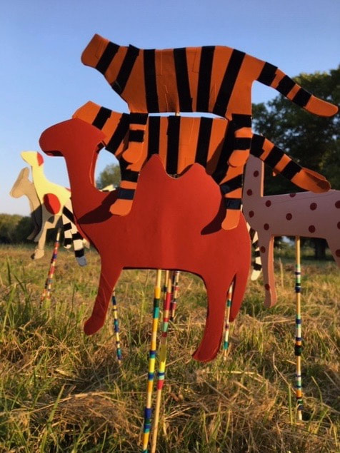 Detail of cutout paper animals on sticks in the grass outside Platt Hall
