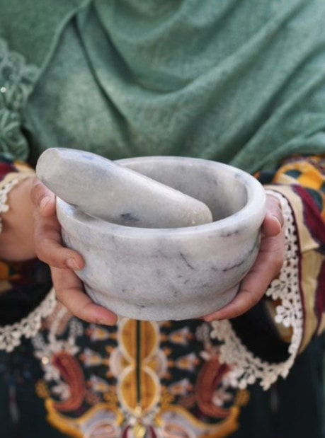 Photograph of a woman holding a pestle and mortar.