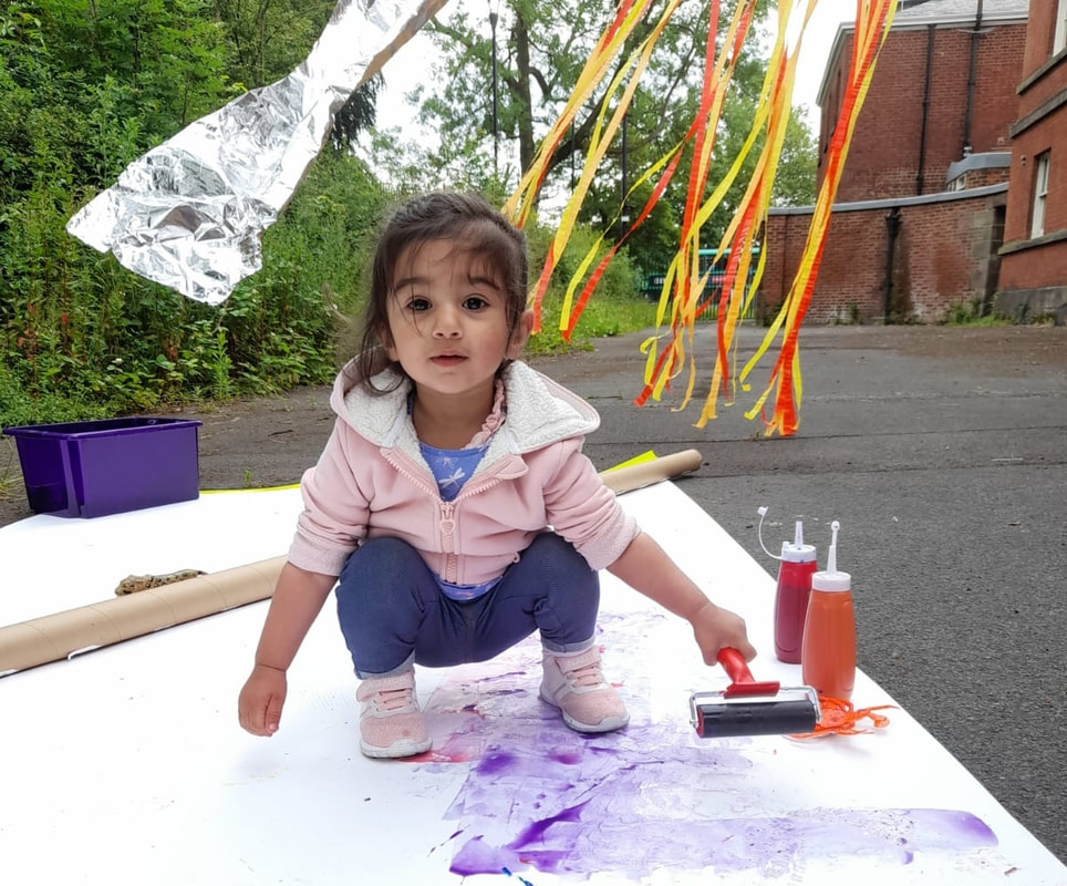 Small child playing with paint and water in the Platt Hall garden.