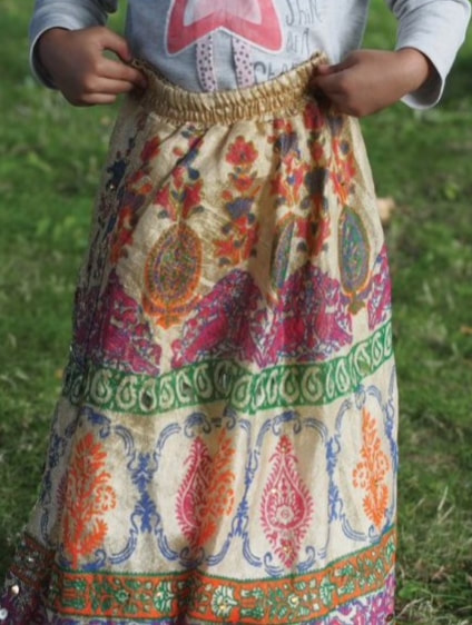 Photograph of a child holding up a colourful skirt.