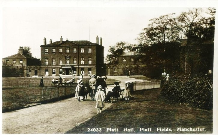 Postcard of Platt Hall in 1910 showing adults and children walking in the park in front of Platt Hall.