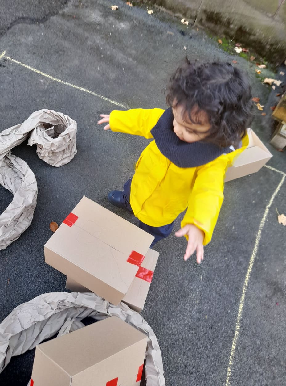 Small child playing with cardboard boxes in the Platt Hall garden