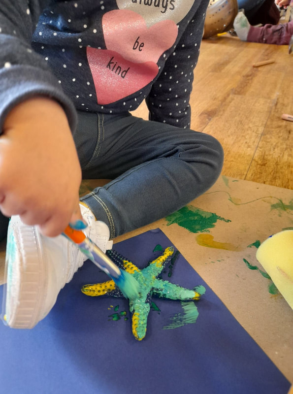 Detail of small child painting a plastic starfish toy